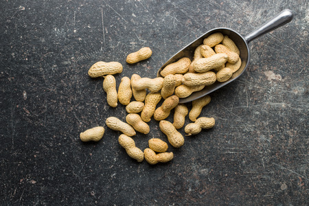 The dried peanuts. Groundnuts in scoop on old table. Top view.