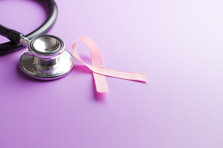 Pink breast cancer ribbon. Breast cancer symbol and stethoscope on violet background.の写真素材