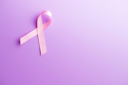Pink breast cancer ribbon. Breast cancer symbol on violet background. Top view.の写真素材