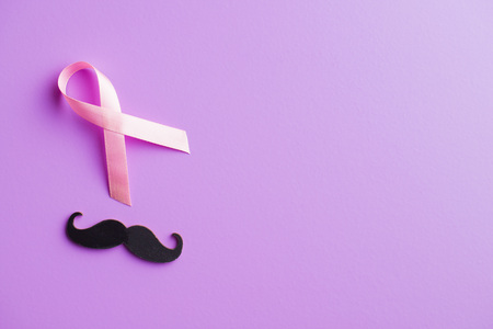 Pink breast cancer ribbon and mustache. Breast cancer and prostate cancer symbol on violet background. Top view.の写真素材
