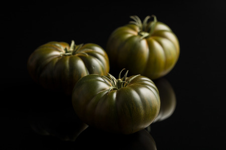 Dark brandywine tomatoes on black background.の写真素材