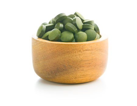 Green chlorella pills or green barley pills in bowl isolated on white background.の写真素材