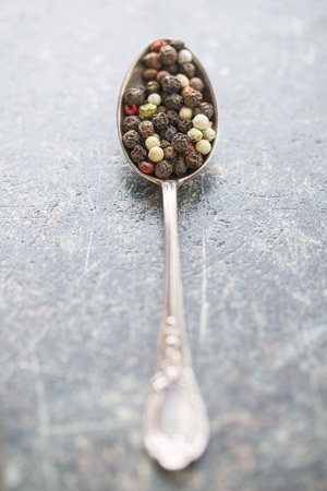 Different types of dried peppercorn in spoon.
