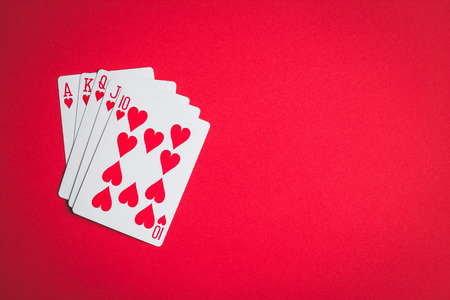 Poker cards. Royal flush on red table.