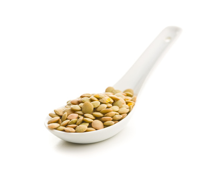 Uncooked dried lentil in ceramic spoon  isolated on white background.の写真素材