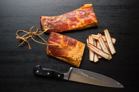 Smoked meat. Tasty bacon on black table. Top view.の写真素材
