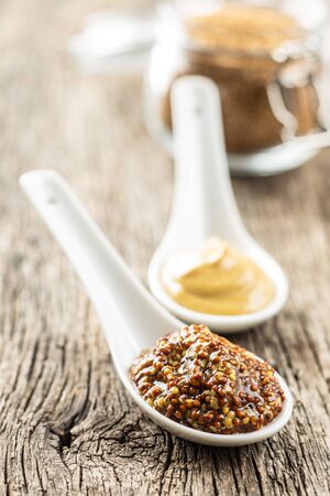 Yellow mustard and whole grain mustard on old wooden table.の写真素材