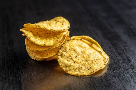 Round nacho chips. Yellow tortilla chips on black table.の写真素材