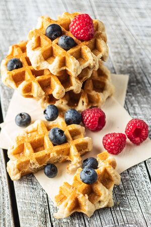 Waffles with blueberries and raspberries on white wooden table.の写真素材