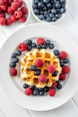 Waffles with blueberries and raspberries on plate. Top view.の写真素材
