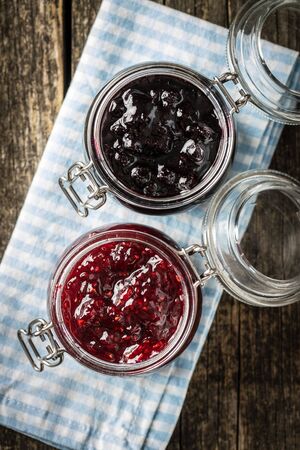 Blueberry and raspberry jam in jar on checkered napkin. Top view.の写真素材