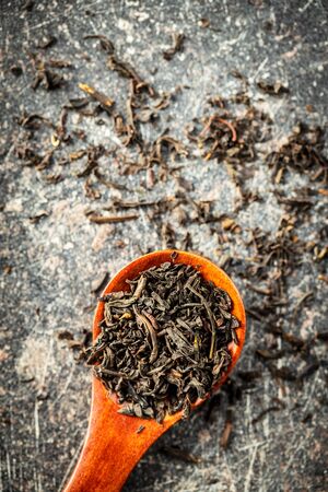 Dried black tea leaves in wooden spoon. Top view.の写真素材