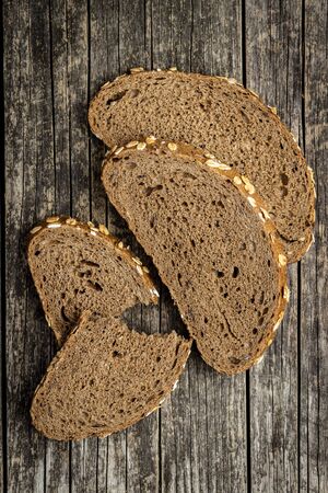 Sliced whole grain bread with oat flakes. Wholemeal bread on old wooden table. Top view.