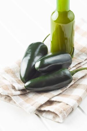 Green jalapeno pepper and tabasco sauce on checkered napkin.の写真素材