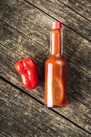 Red habanero pepper and tabasco sauce on old wooden table. Top view.の写真素材