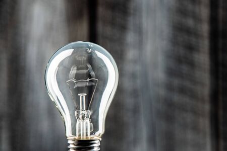 Classic light bulb on front of rustical wall.