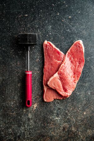 Raw veal schnitzel. Raw meat and meat mallet. Top view.の写真素材