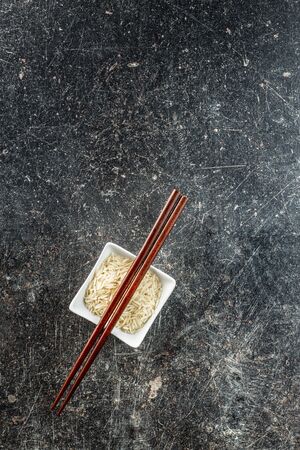 Uncooked indian long rice in bowl and chopsticks. Top view.の写真素材
