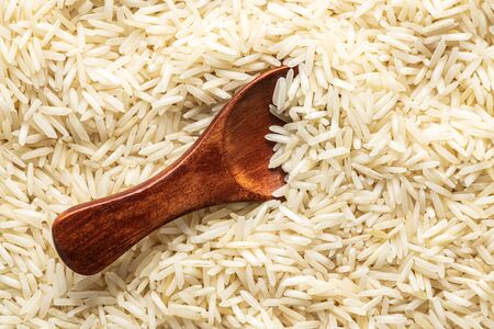Uncooked indian long rice and wooden spoon. Top view.の写真素材