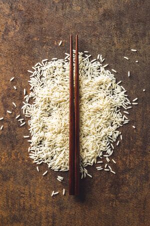Uncooked indian long rice and chopsticks.の写真素材