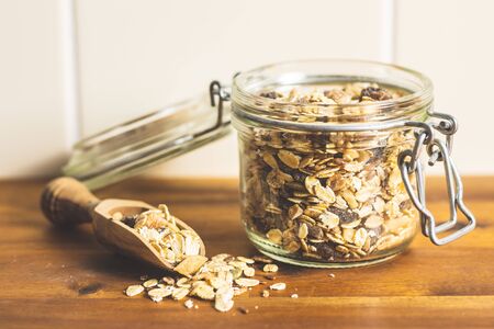 Healthy cereal breakfast. Mixed muesli in jar on wooden table.