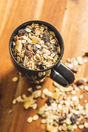 Healthy cereal breakfast. Mixed muesli in cup on old wooden table.