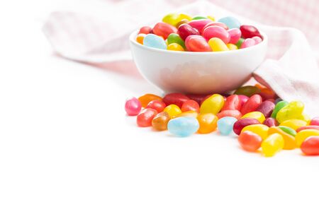 Fruity jellybeans. Tasty colorful jelly beans in bowl isolated on white background.の写真素材