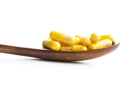 Vitamin capsules in wooden spoon. Vitamin C pills isolated on white background.の写真素材