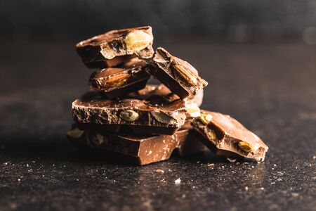 Dark nut chocolate. Broken chocolate bar on black kitchen table. Pile of chocolate.の写真素材
