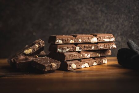 Milk chocolate bars. Brown nut chocolate on wooden table.の写真素材