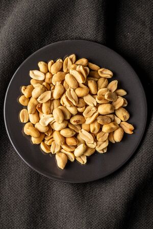 Roasted salted peanuts. Crispy nuts on plate. Top view.