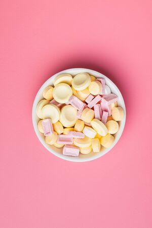 Mix of hard colorful candies in bowl on pink background. Top view.の写真素材