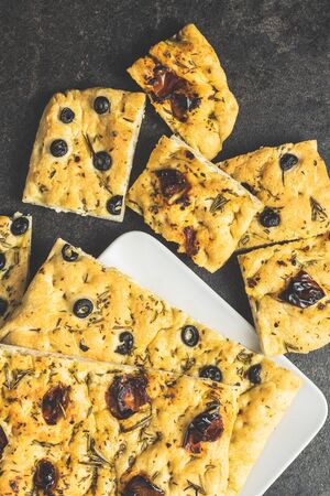 Homemade Italian Focaccia. Traditional Italian pastries with black olives and dried tomatoes. Top view.の写真素材