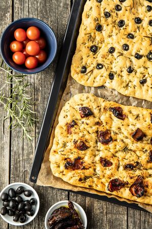 Homemade Italian Focaccia. Traditional Italian pastries with black olives and dried tomatoes. Top view.の写真素材
