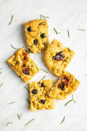 Homemade Italian Focaccia. Traditional Italian pastries with dried tomatoes and olives on kitchen table. Top view.