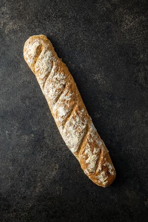 Fresh whole grain bread baguette on black table. Top view.の写真素材