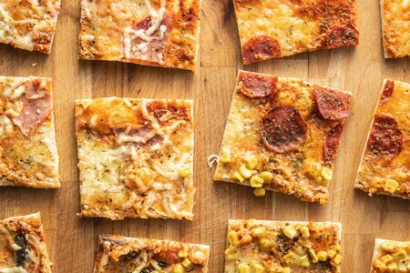 Pieces of homemade Italian pizza on baking paper. Top view.