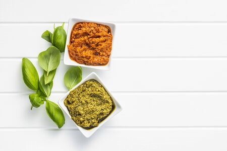Green basil and red tomato pesto dip sauce  and basil leaves on white table. Top view.の写真素材