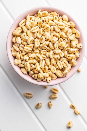 Puffed wheat covered with honey in bowl on white table. Top view.の写真素材