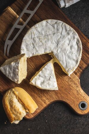 Brie cheese. White soft cheese with white mold on cutting board. Top view.
