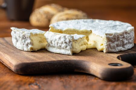 Brie cheese. White soft cheese with white mold on cutting board.