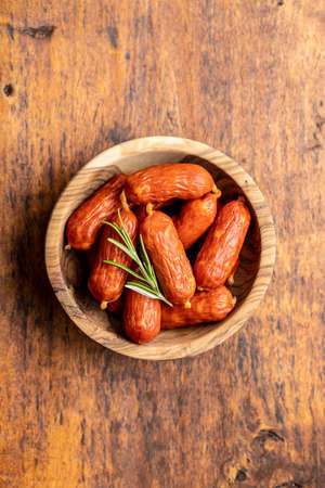 Mini salami sausages in bowl on wooden table. Top view.の写真素材