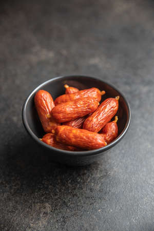 Mini salami sausages in bowl on black table.の写真素材