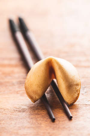 Chinese lucky cookies. Fortune cookies on chopsticks on wooden table.の写真素材