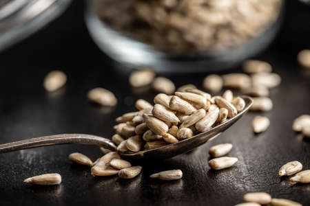 Peeled sunflower seeds in silver spoon on black table