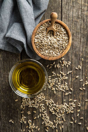 Peeled sunflower seeds and oil on old wooden table. Top view.の写真素材