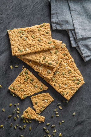 The crispy bread with pumpkin seeds. Knackebrot on black table. Top view.