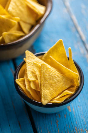 Salted tortilla chips on blue table.