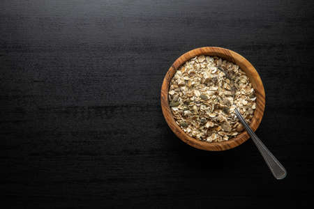 Muesli cereals. Healthy breakfast with oats flakes in bowl on black table. Top view.