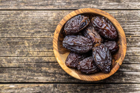 Dried dates fruit in wooden bowl on wooden table. Top view.の写真素材